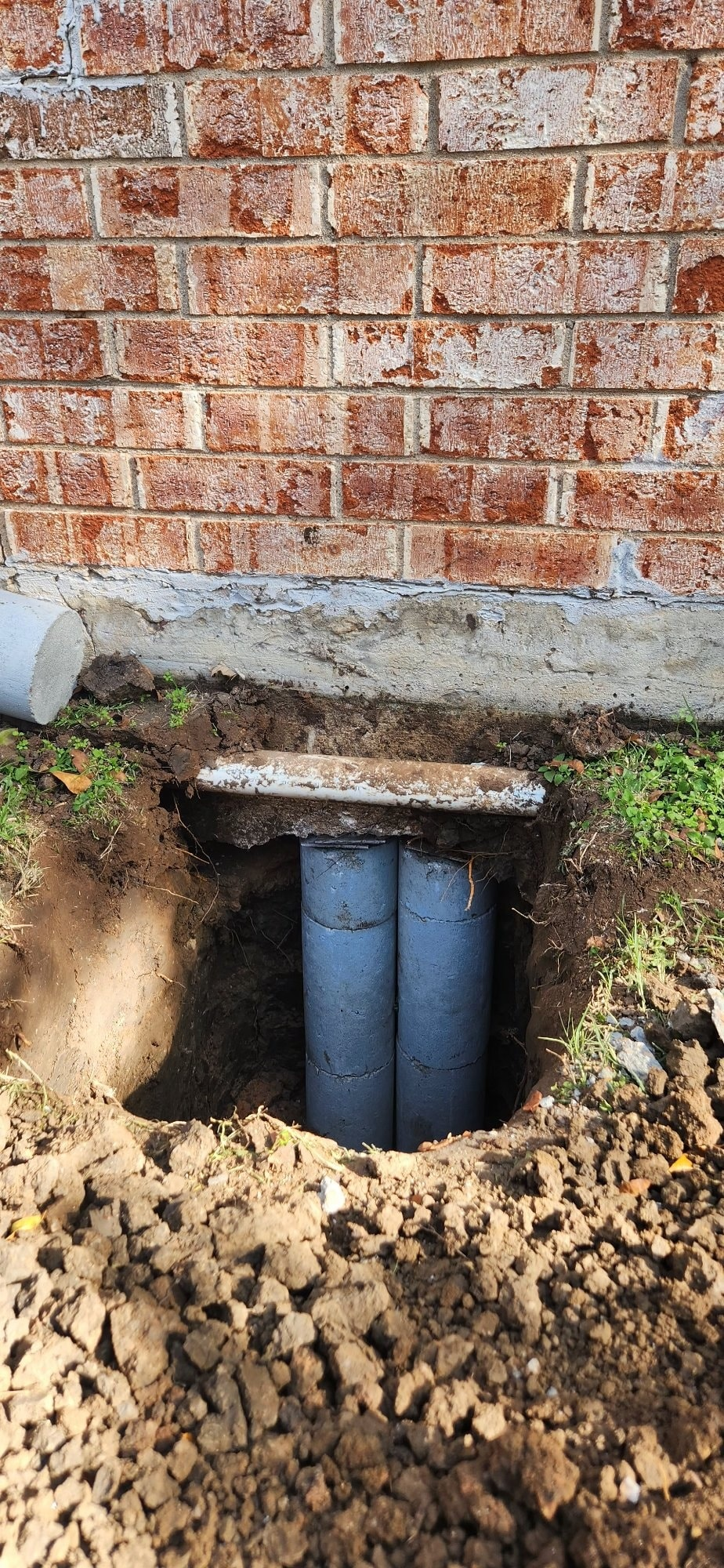 Concrete piers installed next to a brick wall foundation